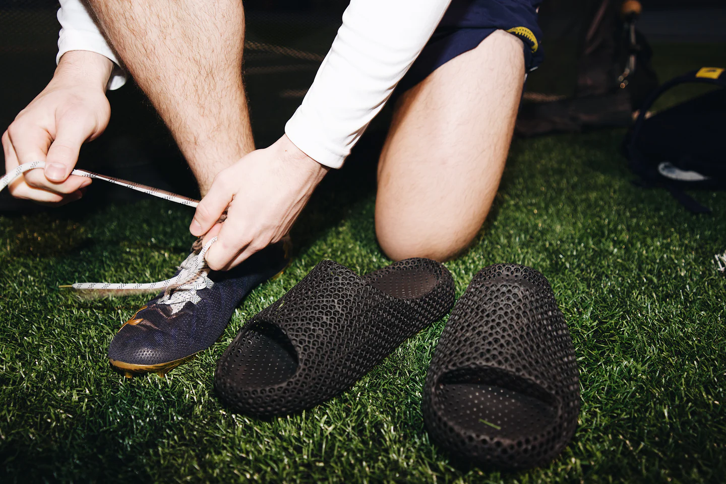 Athlete tying cleats with Wov3 recovery clogs